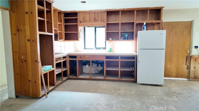 kitchen featuring open shelves, concrete floors, light countertops, and freestanding refrigerator