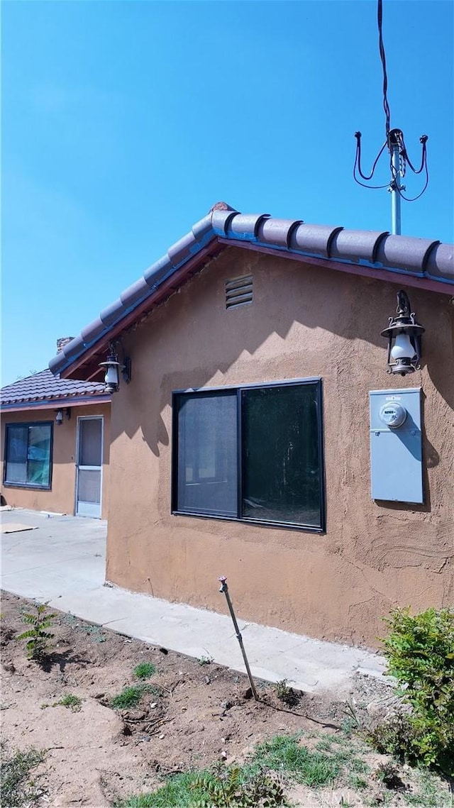 view of side of home with stucco siding and a tile roof