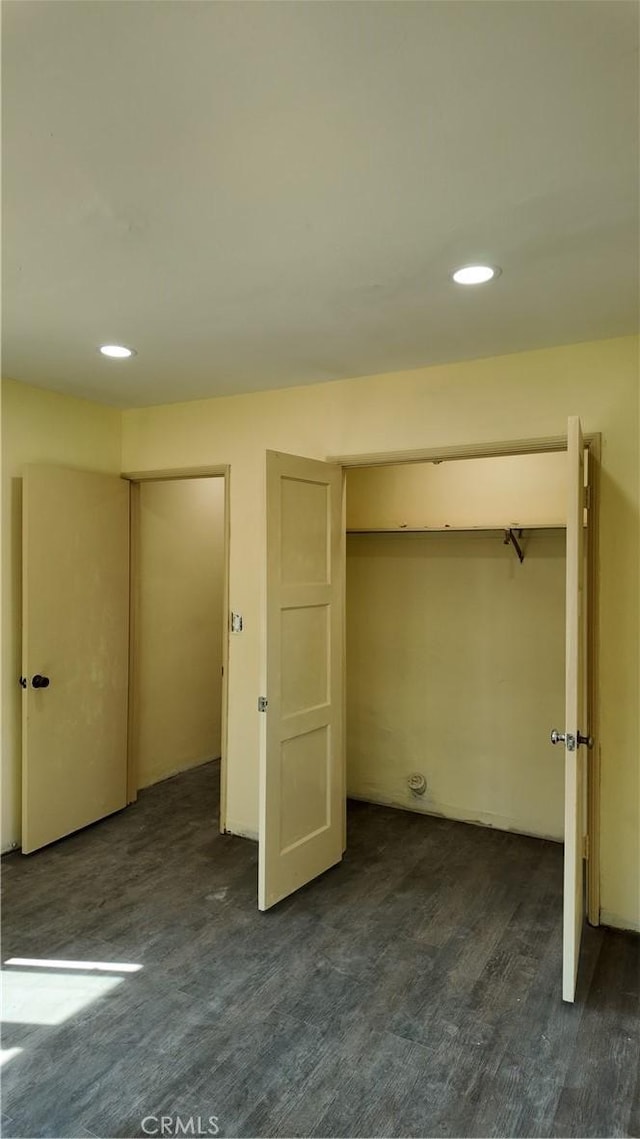 unfurnished bedroom featuring recessed lighting, a closet, and dark wood-type flooring