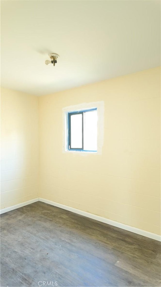 unfurnished room featuring baseboards and dark wood-style flooring