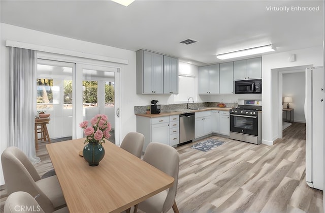 kitchen with stainless steel appliances, wood counters, a sink, visible vents, and light wood-style floors