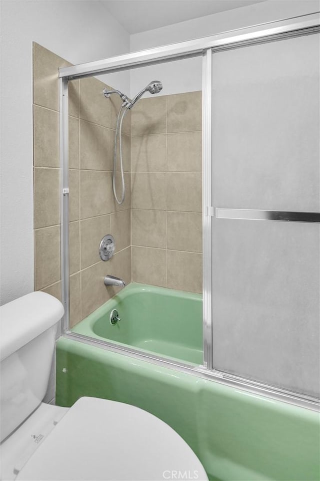 full bath featuring toilet and shower / bath combination with glass door