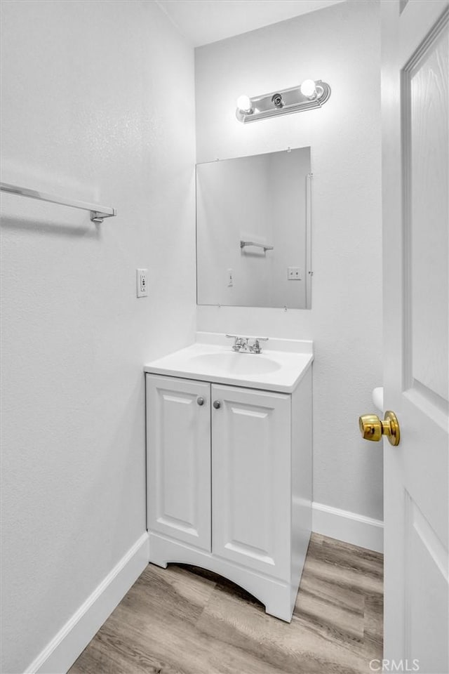 bathroom with baseboards, wood finished floors, and vanity