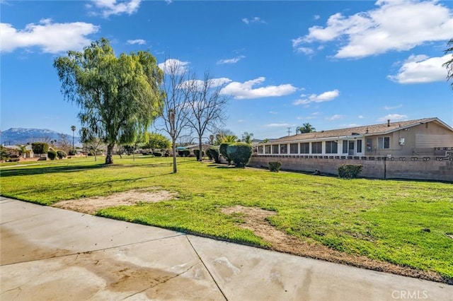 surrounding community with a lawn, fence, and a mountain view