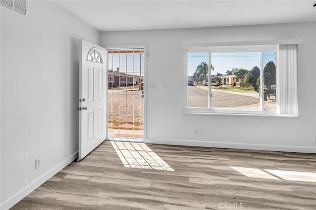 interior space with light wood-style floors, visible vents, and baseboards