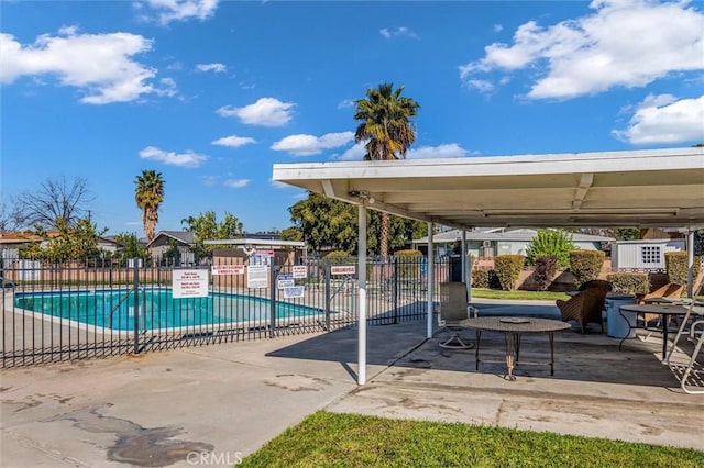 community pool with a patio area and fence