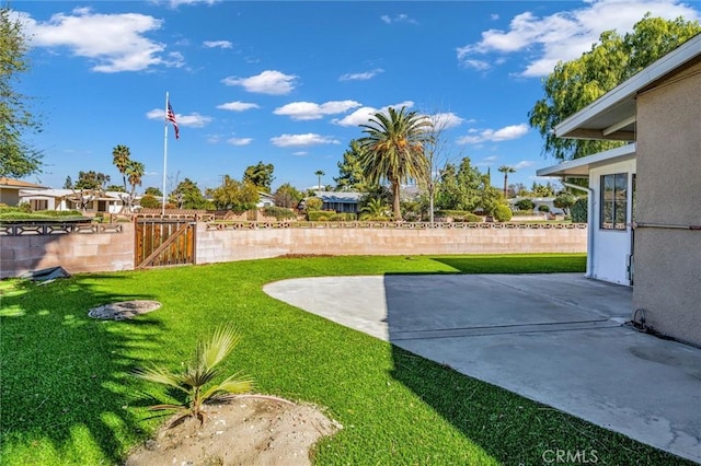 view of yard with a gate, fence, and a patio