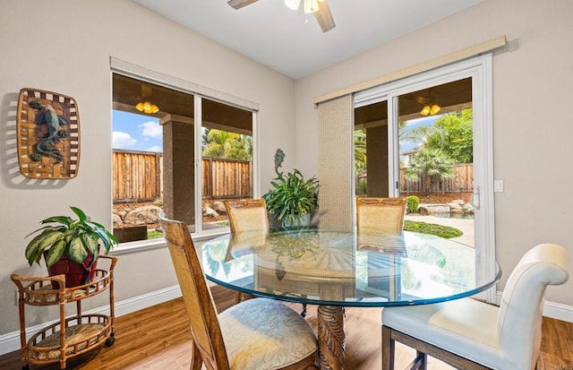 dining space with a ceiling fan, baseboards, and wood finished floors