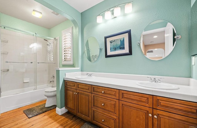 bathroom with double vanity, a sink, toilet, and wood finished floors