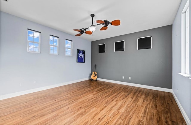 unfurnished room featuring plenty of natural light, baseboards, and wood finished floors