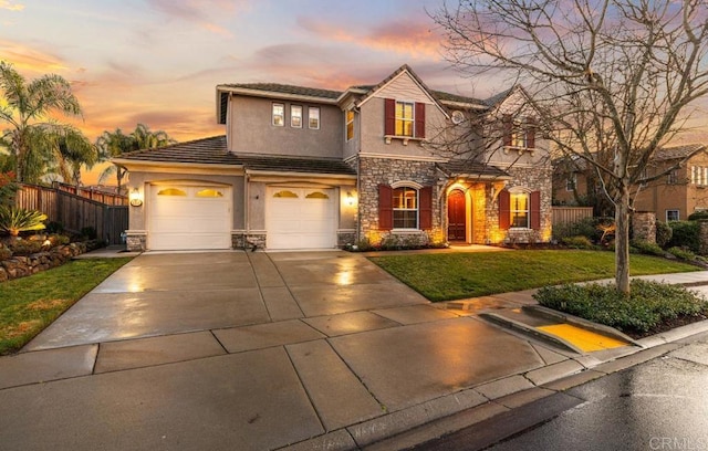 view of front of house featuring stucco siding, a front yard, fence, a garage, and stone siding