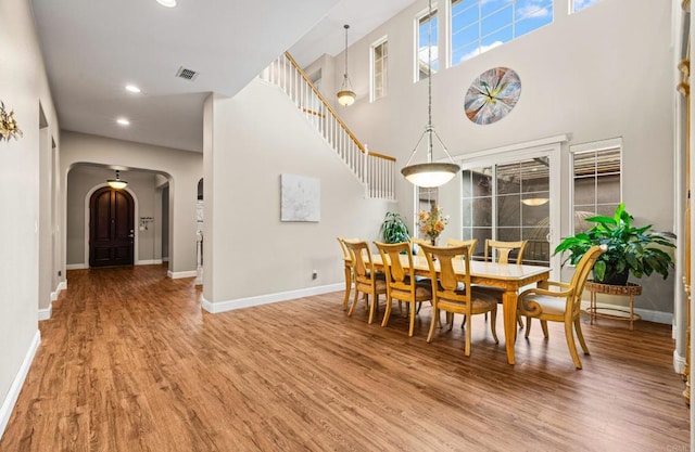 dining space with arched walkways, wood finished floors, visible vents, and baseboards