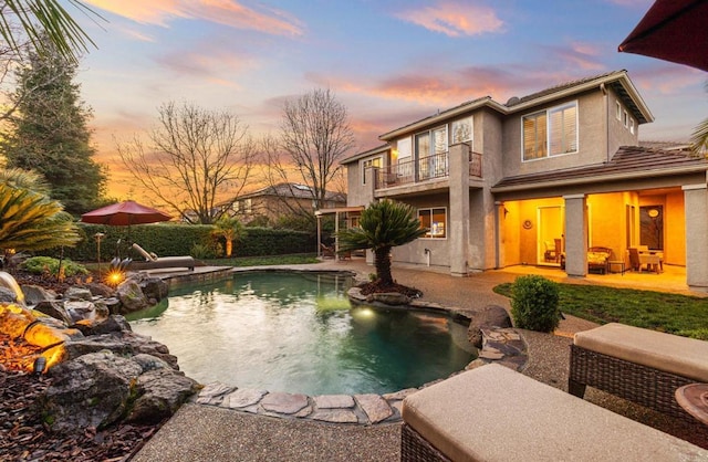 pool at dusk with a patio area and an outdoor pool