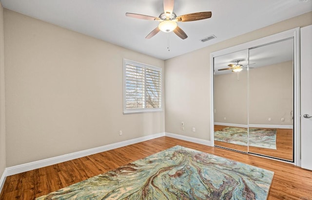 bedroom featuring ceiling fan, wood finished floors, visible vents, and baseboards