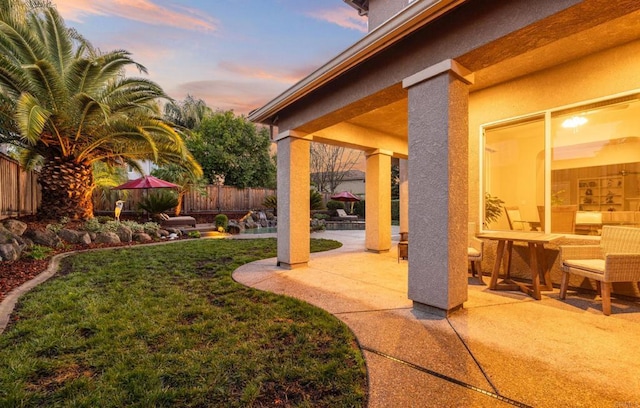 yard at dusk featuring a fenced backyard and a patio