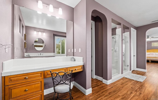 ensuite bathroom with a shower stall, connected bathroom, baseboards, and wood finished floors