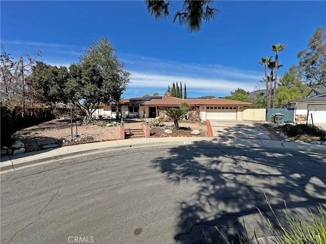 view of front of property featuring a garage, fence, solar panels, and concrete driveway