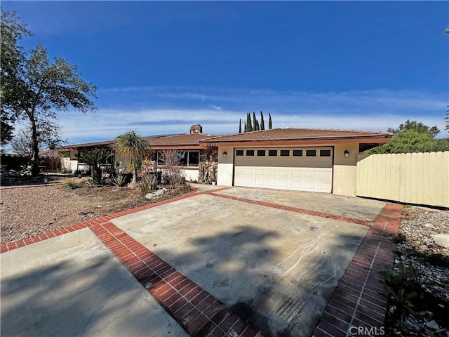 view of front of house featuring driveway, an attached garage, fence, and stucco siding