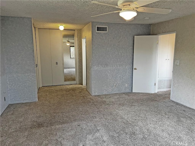 spare room featuring a textured ceiling, ceiling fan, carpet, and visible vents