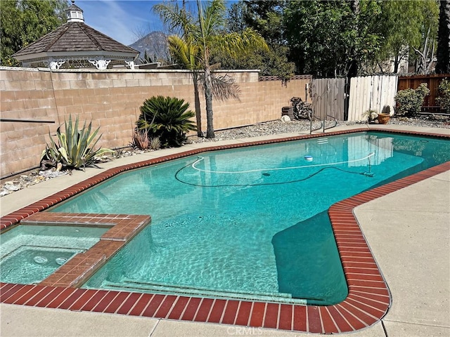 view of pool with a fenced in pool, a fenced backyard, a gazebo, and an in ground hot tub