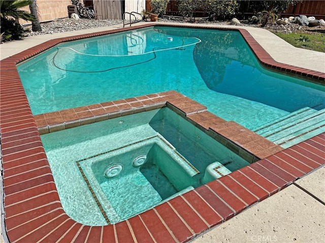 view of pool featuring a fenced in pool, fence, and an in ground hot tub