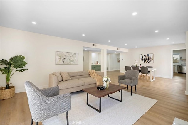 living room featuring baseboards, light wood-style flooring, and recessed lighting