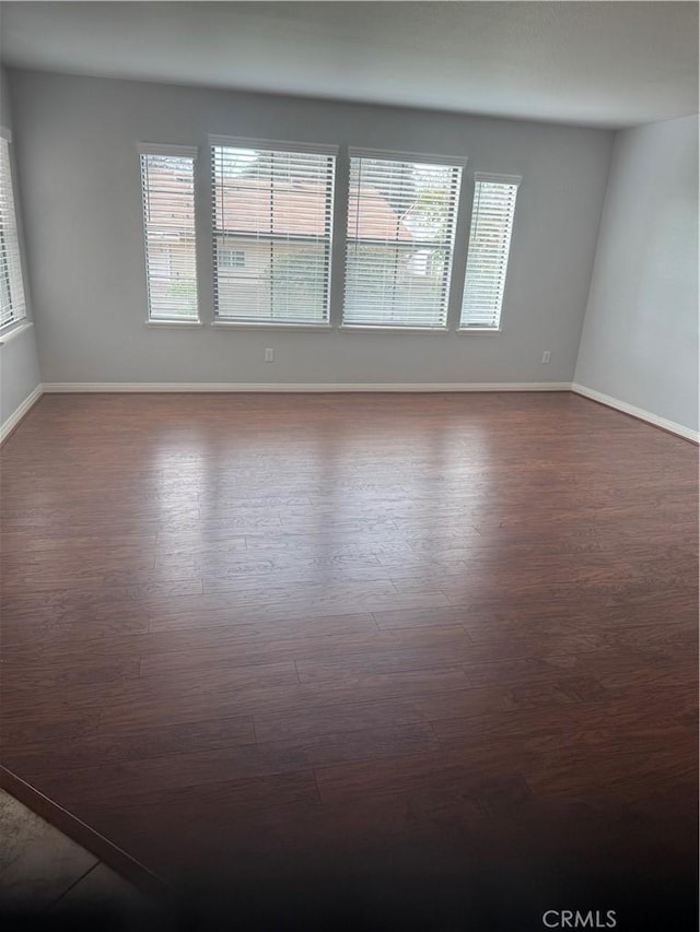 empty room with dark wood finished floors and baseboards