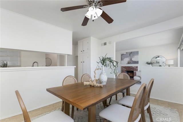 dining room with light tile patterned floors, a brick fireplace, and visible vents