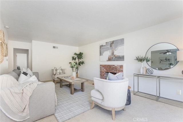 living room with light carpet, a brick fireplace, and visible vents