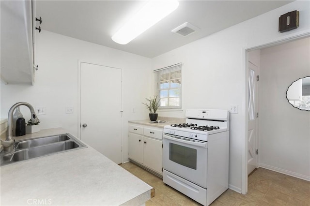 kitchen featuring white gas stove, a sink, visible vents, white cabinetry, and light countertops