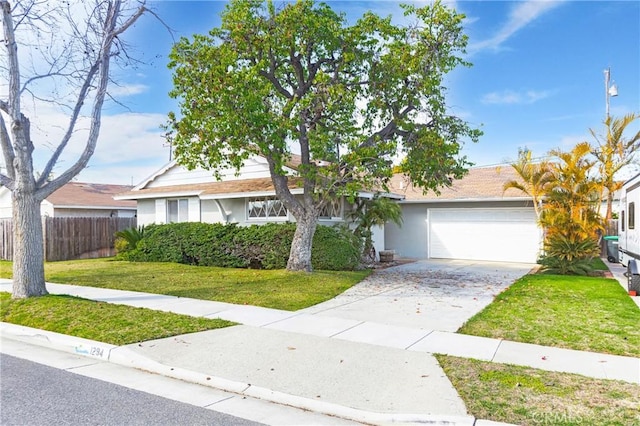 view of front facade featuring stucco siding, concrete driveway, an attached garage, a front yard, and fence