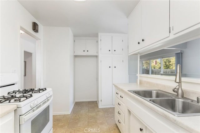 kitchen featuring white gas stove, light countertops, white cabinetry, a sink, and baseboards