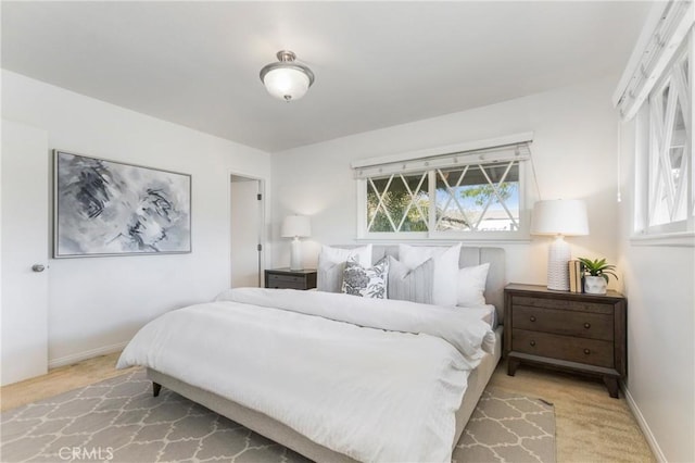 bedroom with light colored carpet, baseboards, and multiple windows