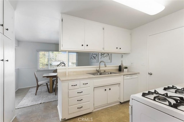 kitchen with white appliances, light countertops, a sink, and white cabinets