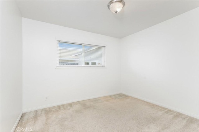 unfurnished room featuring baseboards and light colored carpet