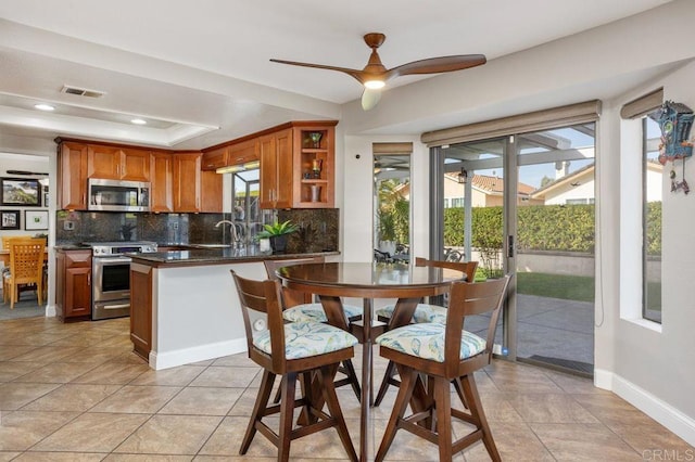 kitchen featuring visible vents, dark countertops, appliances with stainless steel finishes, a peninsula, and a tray ceiling