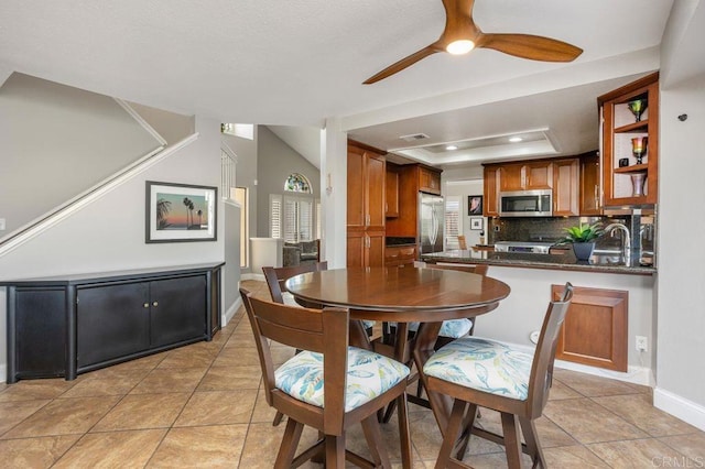 dining area featuring light tile patterned floors, a raised ceiling, a ceiling fan, and baseboards