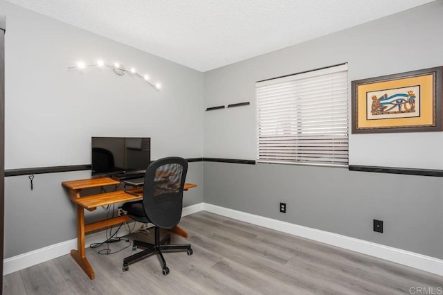 office space with light wood finished floors, baseboards, and a textured ceiling