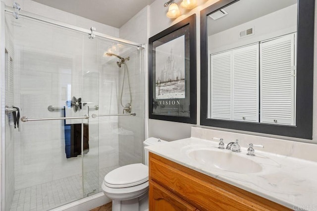 bathroom featuring a closet, visible vents, toilet, a stall shower, and vanity