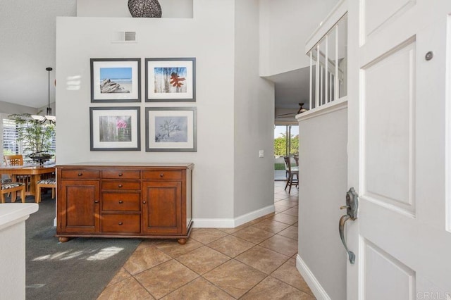 entryway featuring baseboards, visible vents, a high ceiling, and light tile patterned floors