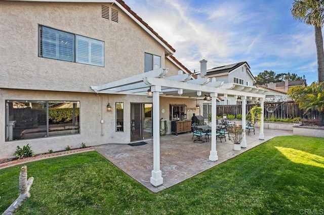 rear view of house featuring a lawn, fence, a patio area, a pergola, and stucco siding