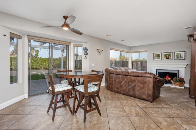 dining area with baseboards, visible vents, ceiling fan, a fireplace, and light tile patterned flooring