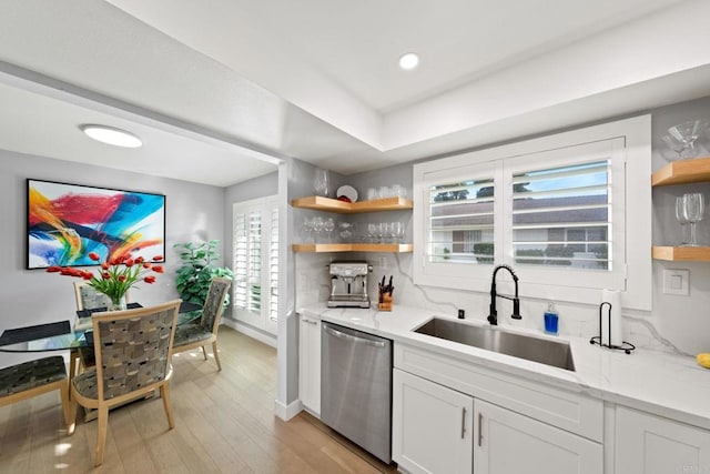 kitchen featuring open shelves, stainless steel dishwasher, a sink, and white cabinets