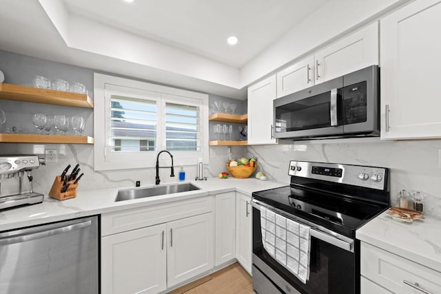 kitchen with appliances with stainless steel finishes, white cabinets, and a sink