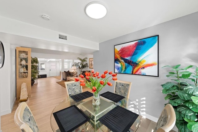 dining room featuring light wood-style floors, visible vents, and baseboards