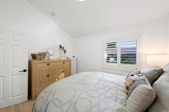 bedroom featuring light wood-type flooring and vaulted ceiling