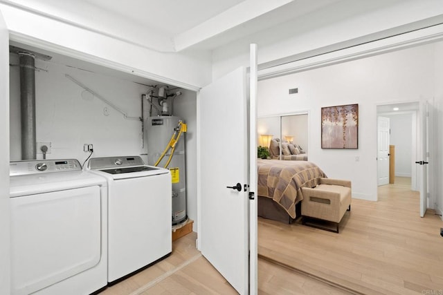 laundry area featuring laundry area, secured water heater, separate washer and dryer, and light wood-style flooring