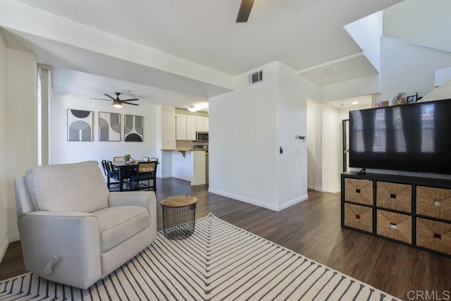 living area featuring baseboards, dark wood-style flooring, visible vents, and a ceiling fan