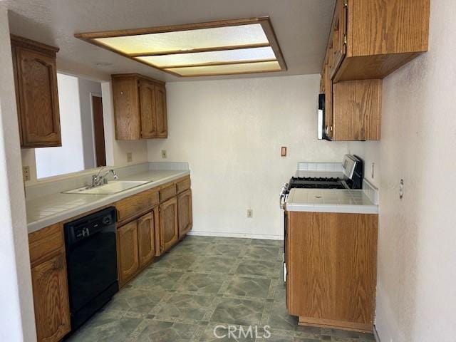 kitchen with black dishwasher, brown cabinets, light countertops, stainless steel range with gas cooktop, and a sink