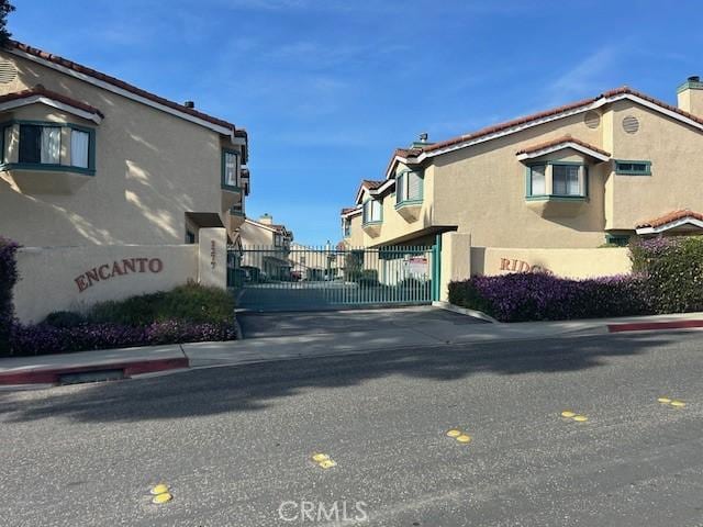 view of road with a residential view, a gate, curbs, and a gated entry